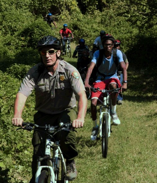 A National Park Service ranger leads an adventurous group on a bike ride through DC's Fort Dupont Park.