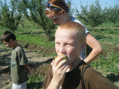 A participant enjoys an apple fresh from the tree during a Boys and Girls Club field trip to a local farm.