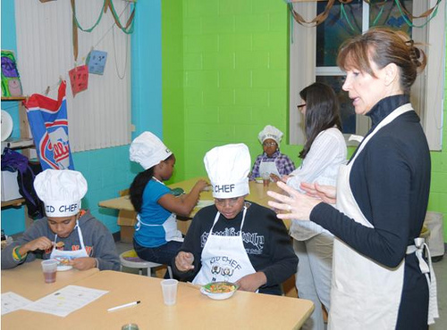 Food Bank of Delaware community nutritionist Beverly Jackey explains the nutritional benefits of the latest dish prepared by her KID CHEF students.  Enjoying the fruits of their newfound culinary skills are (left to right) Zyaire Tolbert, Jamire Fountain, (background left to right) Angela Lee, Tanyah Ramos, and Volunteer Coordinator Leslie McGowan.